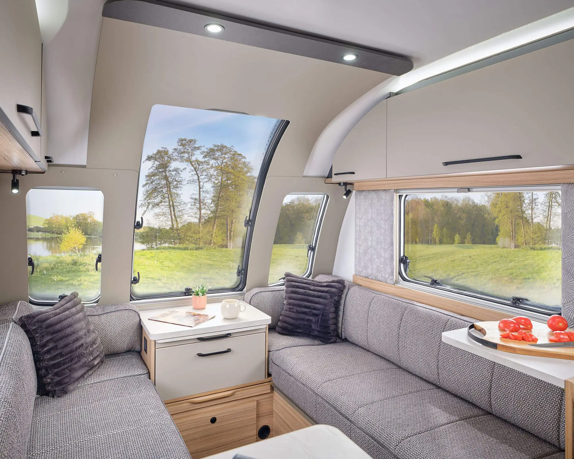 Cozy Interior of a Bailey Caravan with Scenic Views Inviting lounge area inside a Bailey caravan featuring modern furnishings and large windows overlooking a serene landscape.