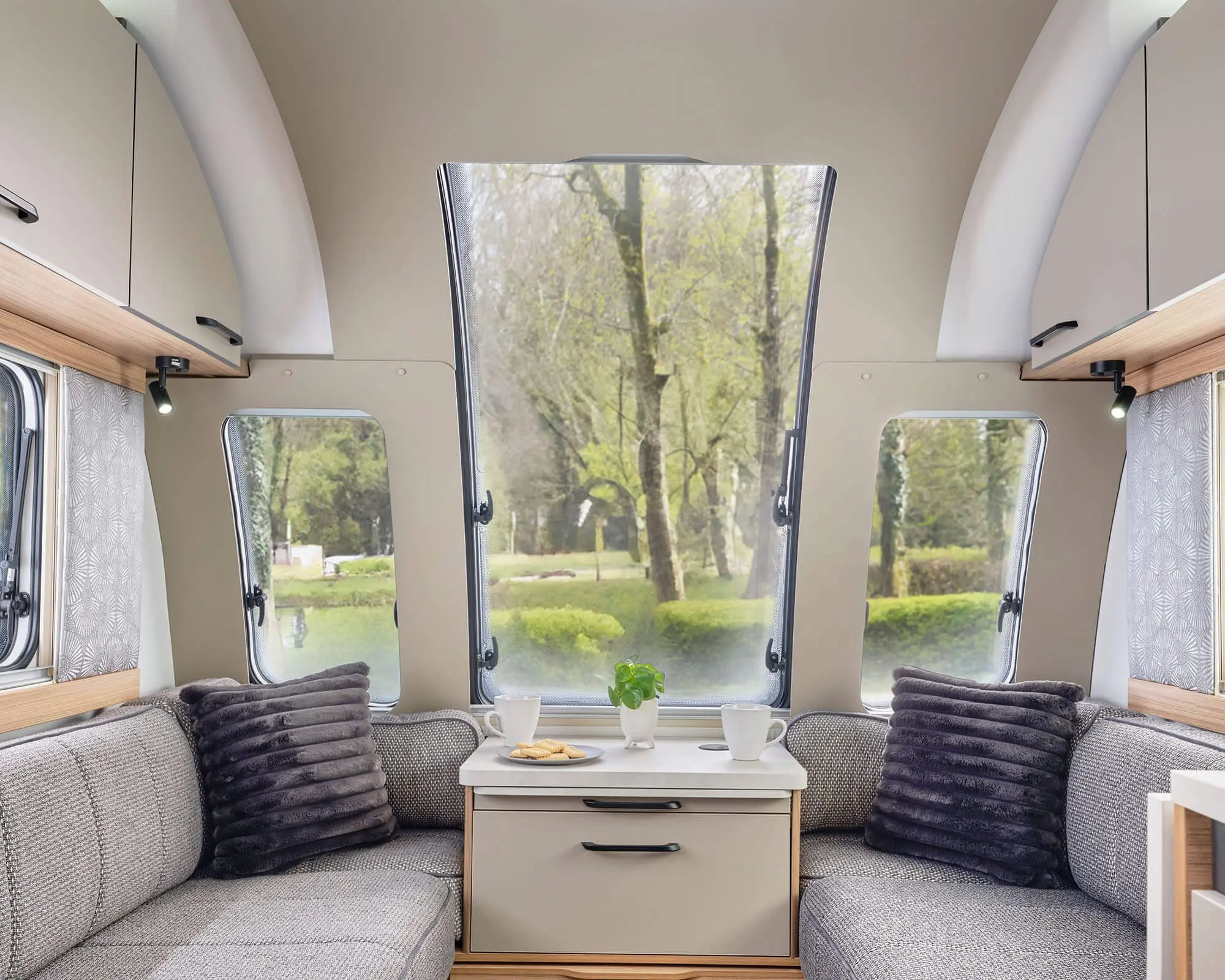 Cozy seating area inside a Bailey caravan with large windows and natural light.