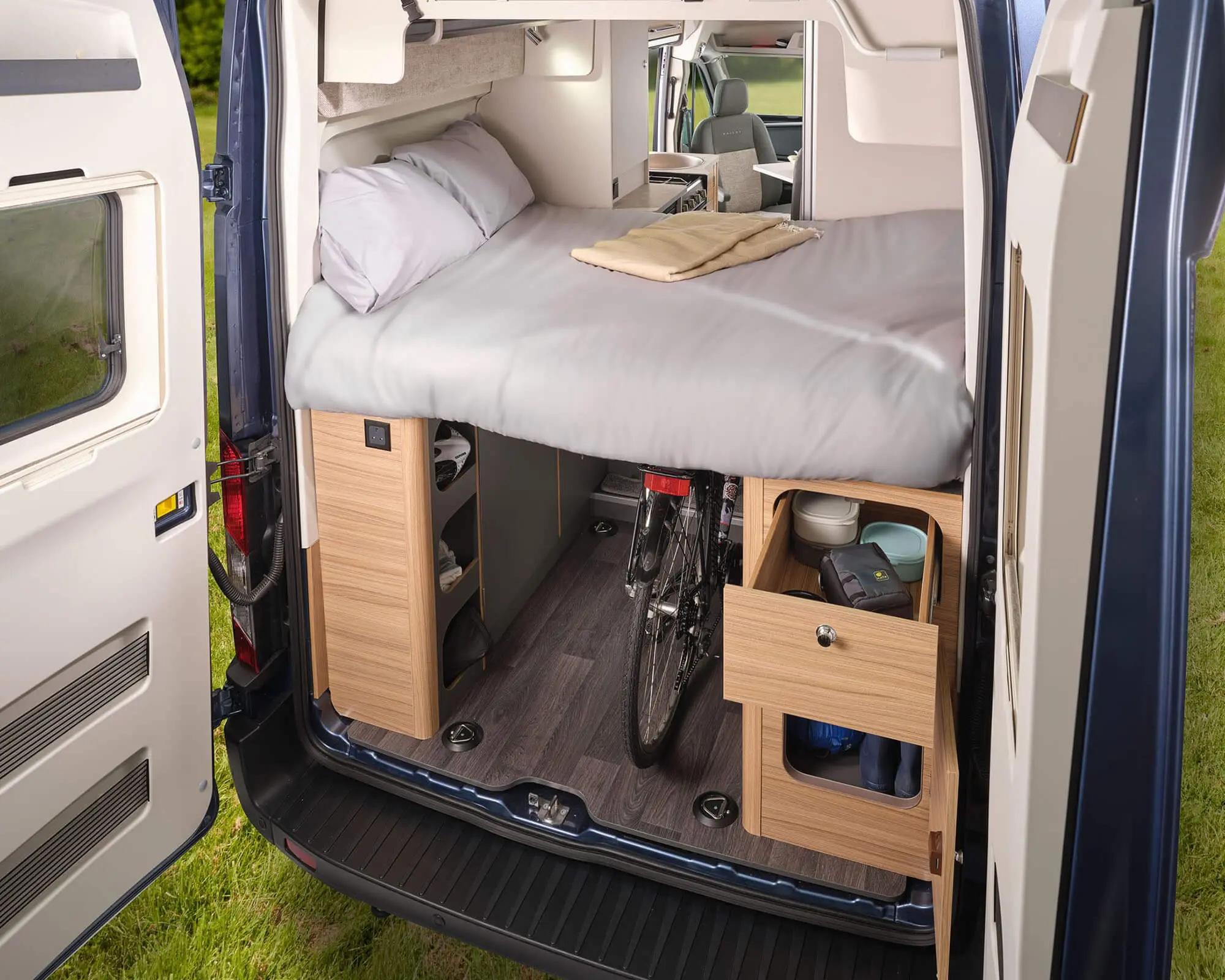 Interior view of a Bailey motorhome featuring a comfortable bed, storage cabinets, and a bicycle.
