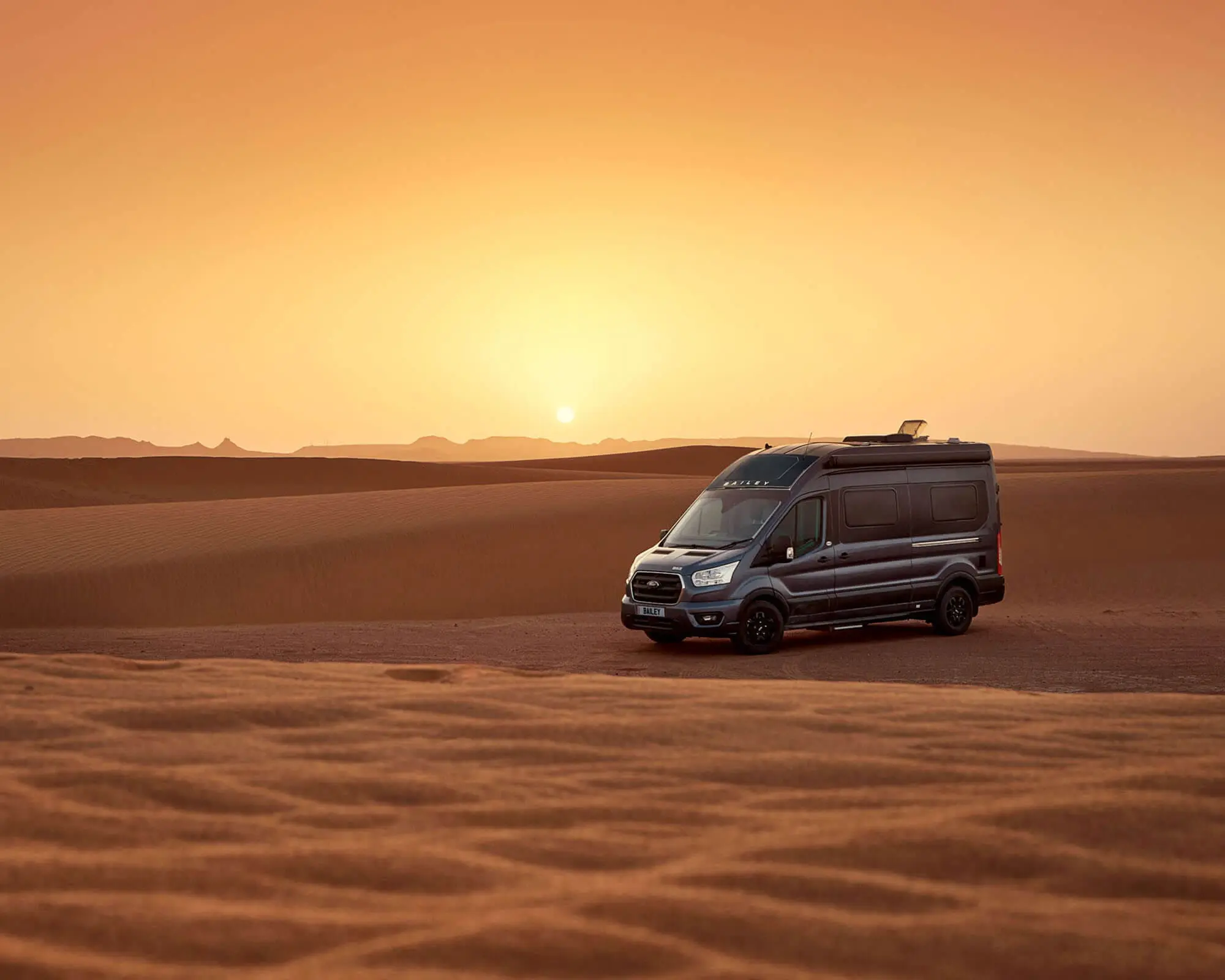 A Bailey motorhome parked in a desert at sunset, highlighting its adventurous spirit and capability for exploring vast landscapes.