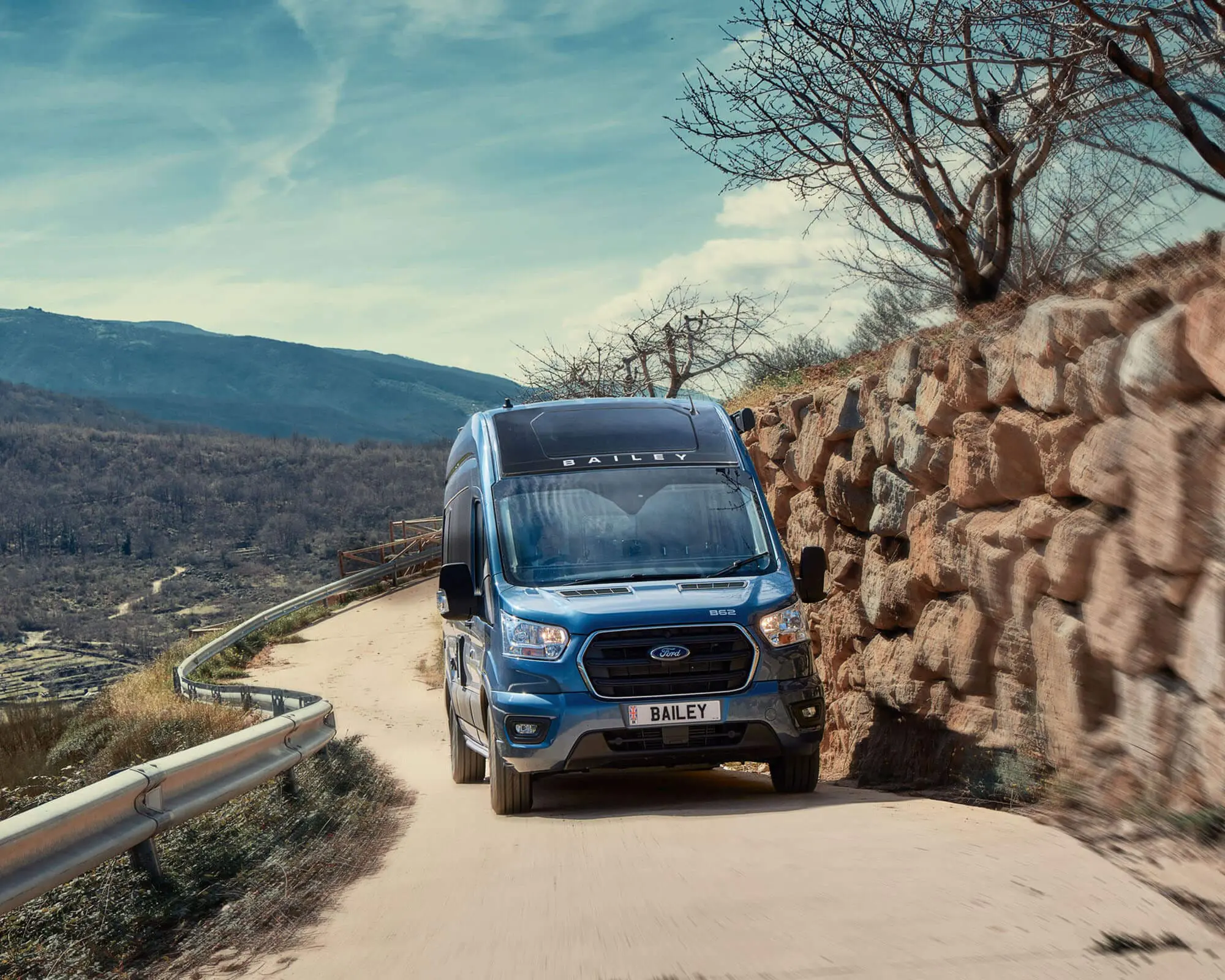 A blue motorhome navigating a winding road surrounded by natural scenery, ideal for outdoor adventures.