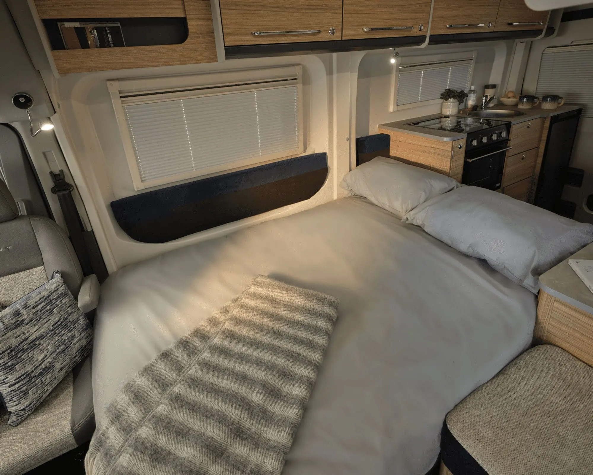 Cozy bed area in a Bailey motorhome, featuring warm lighting and wooden accents.