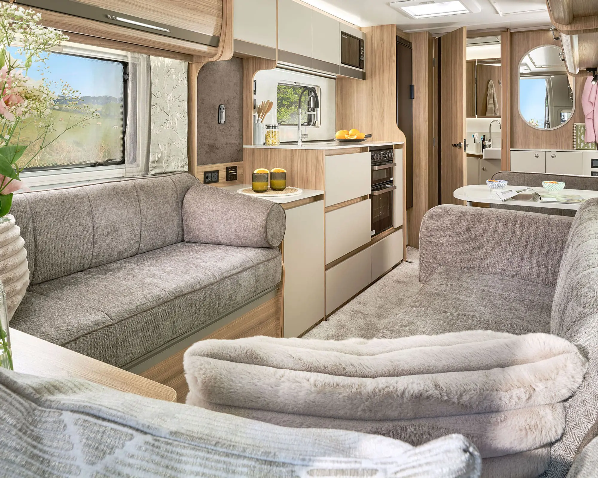 Cozy and stylish interior of a Bailey caravan featuring comfortable seating and a well-equipped kitchen area.