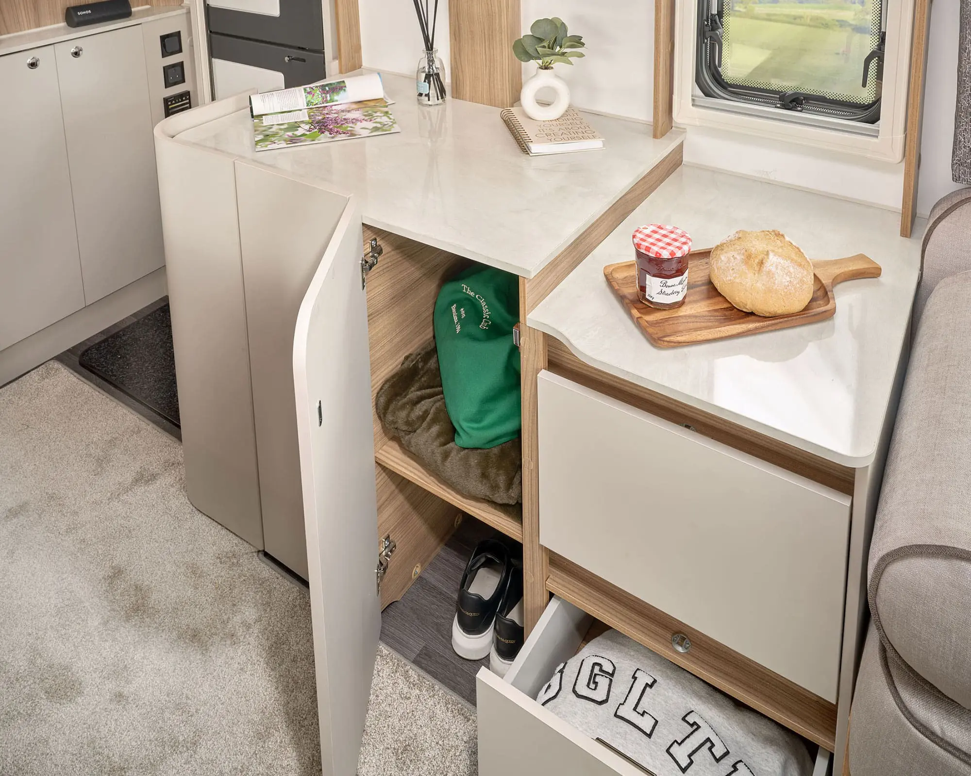 Compact storage area in a Bailey caravan featuring shelves and a workspace with breakfast items.