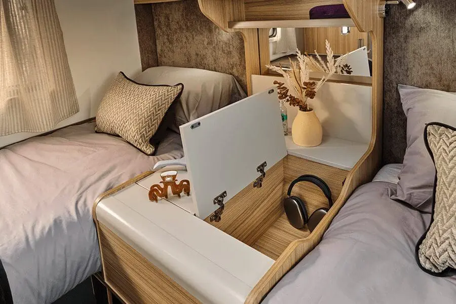 Interior of a Bailey Caravan with Twin Beds and Central Features Cozy interior view of a Bailey caravan showcasing twin beds, a central storage unit, and decorative items.