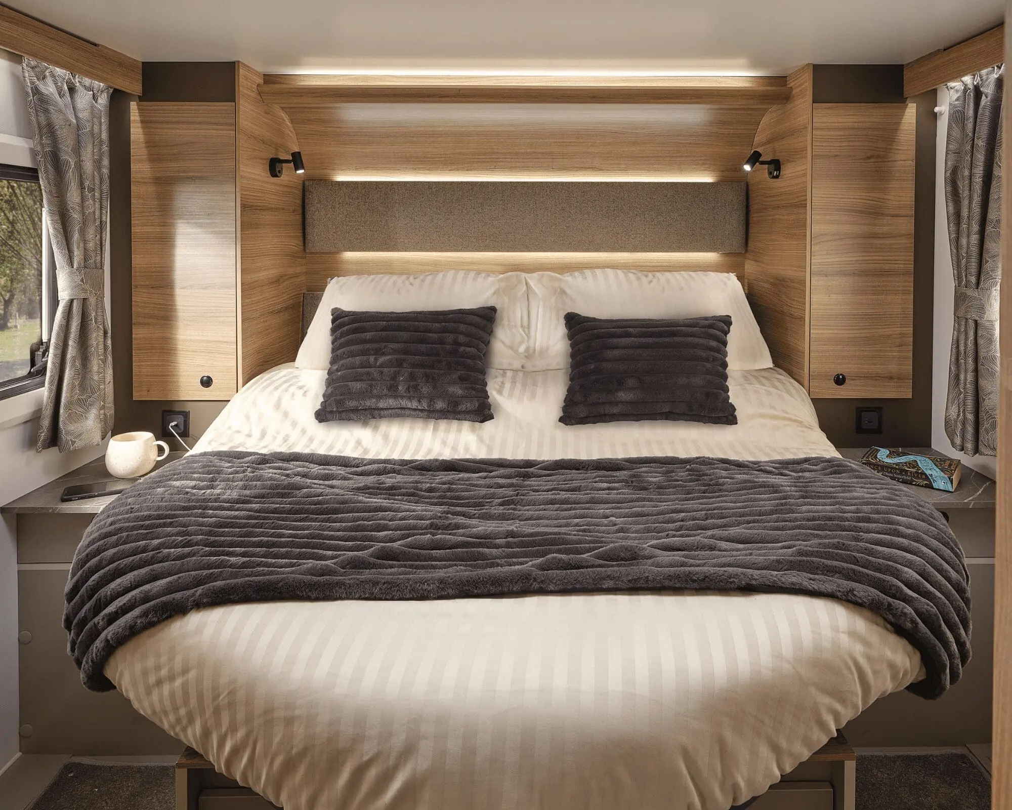 Stylish and comfortable bedroom setup featuring a double bed with plush pillows in a Bailey motorhome.