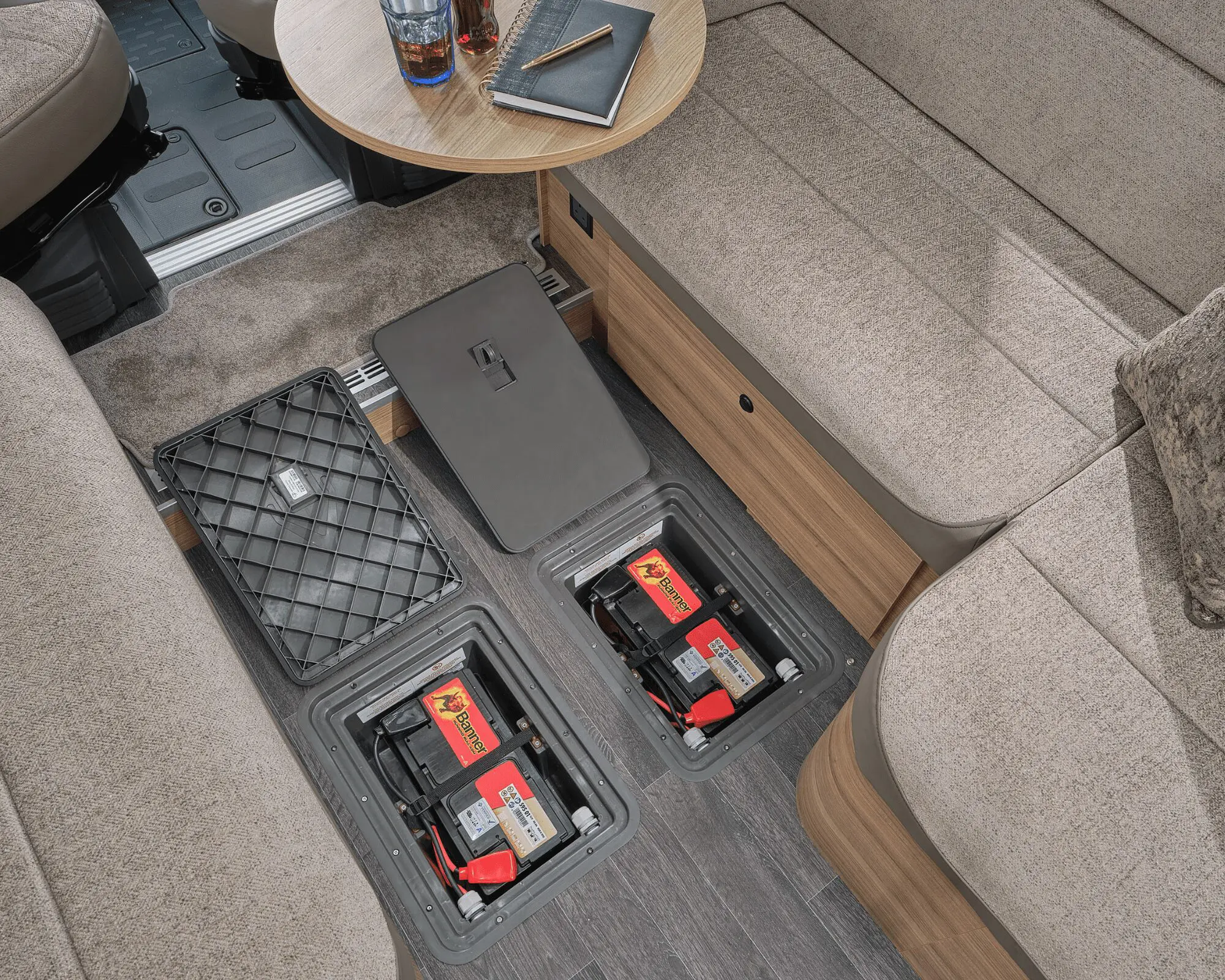 View of the floor area in a Bailey motorhome showing battery storage compartments and a cozy seating arrangement.