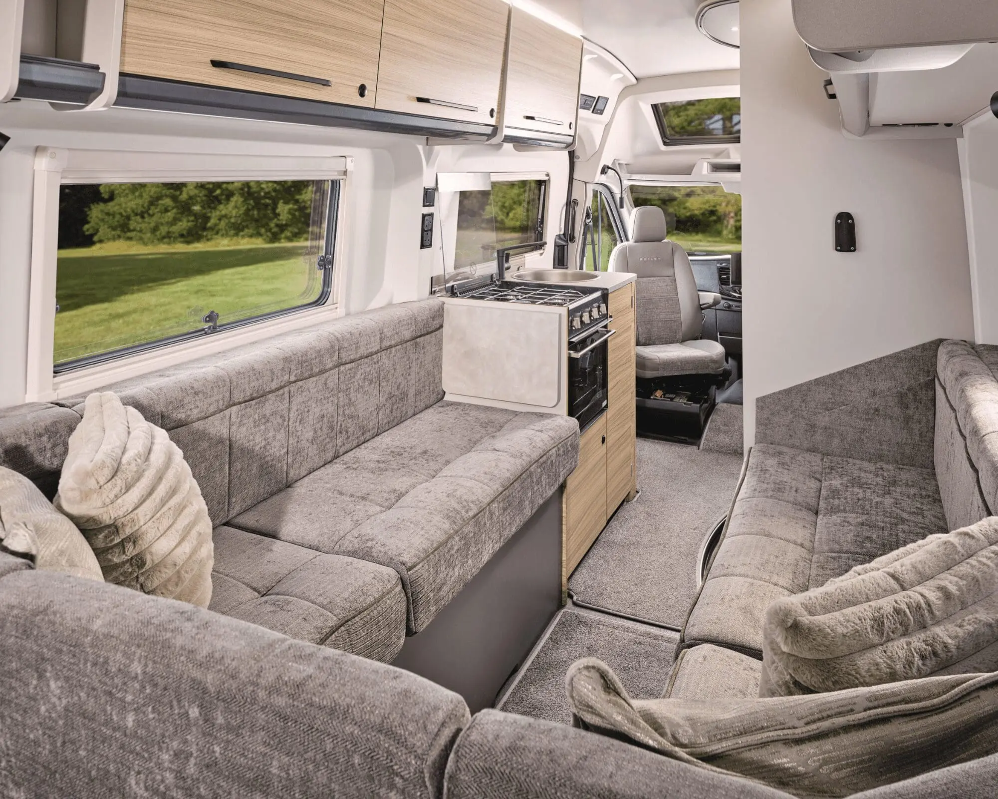 Cozy living area inside a Campervan with grey seating and kitchenette, ideal for camping adventures