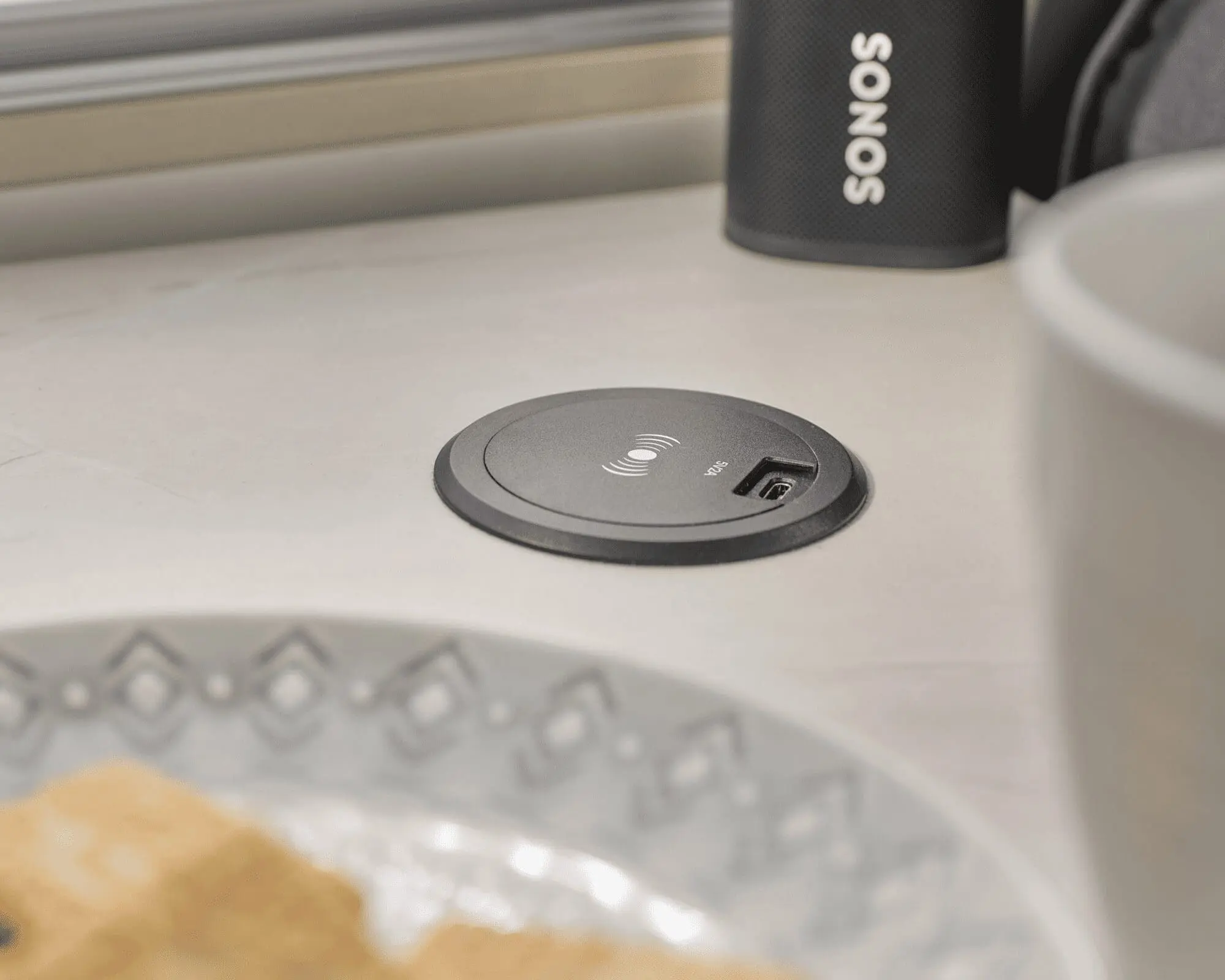 Convenient Power Socket in a Caravan Setup A close-up of a power socket on a countertop with a plate and a cup nearby, showcasing modern amenities in a caravan.