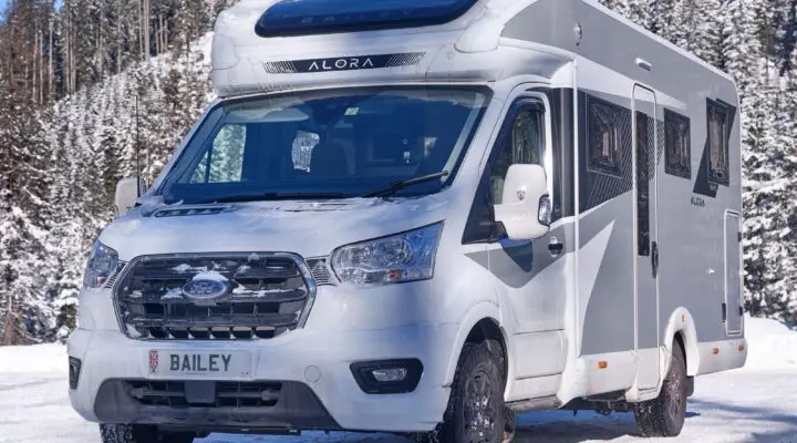 A Bailey motorhome parked in a snowy environment, surrounded by trees.