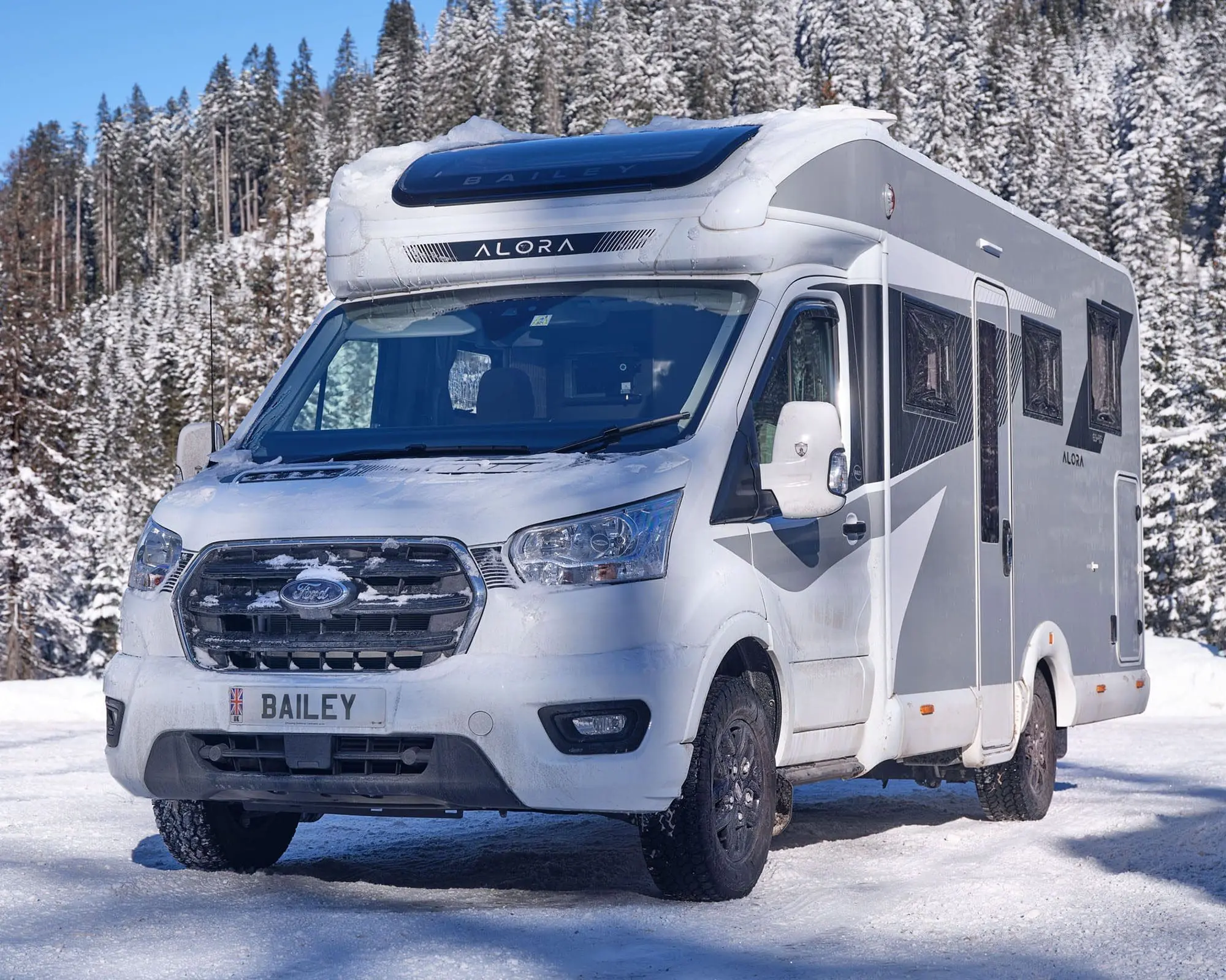 A Bailey motorhome parked in a snowy environment, surrounded by trees.