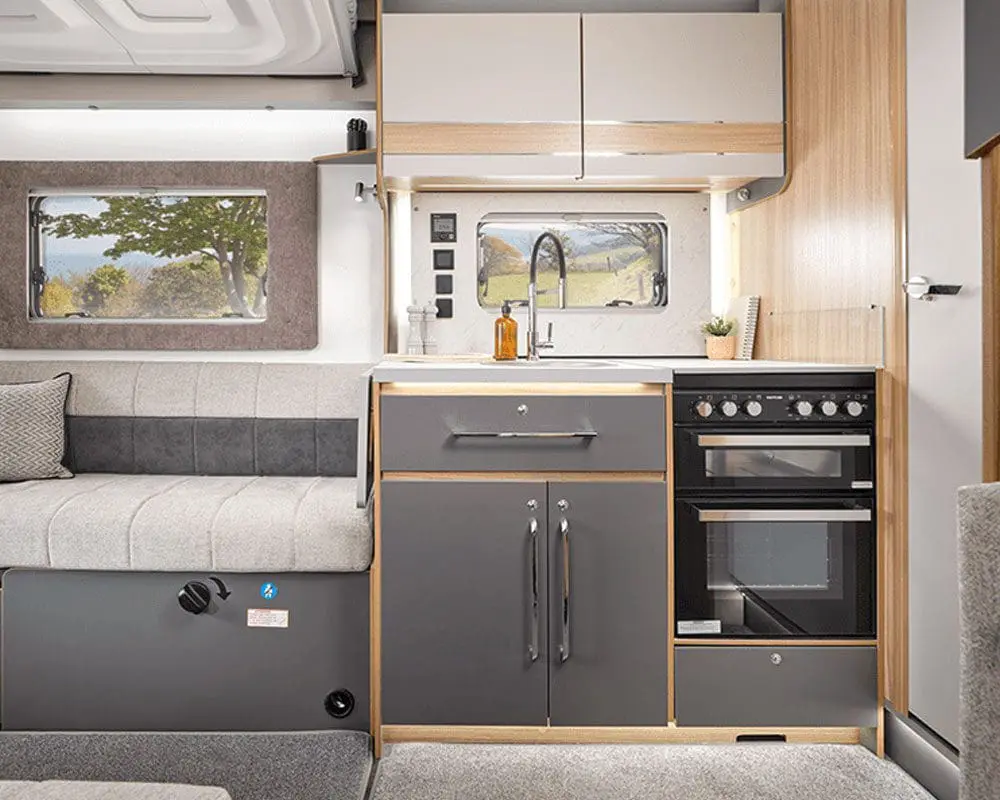 Modern and Compact Kitchen in a Caravan Interior view of a stylish caravan kitchen featuring a sink, stove, and storage cabinets