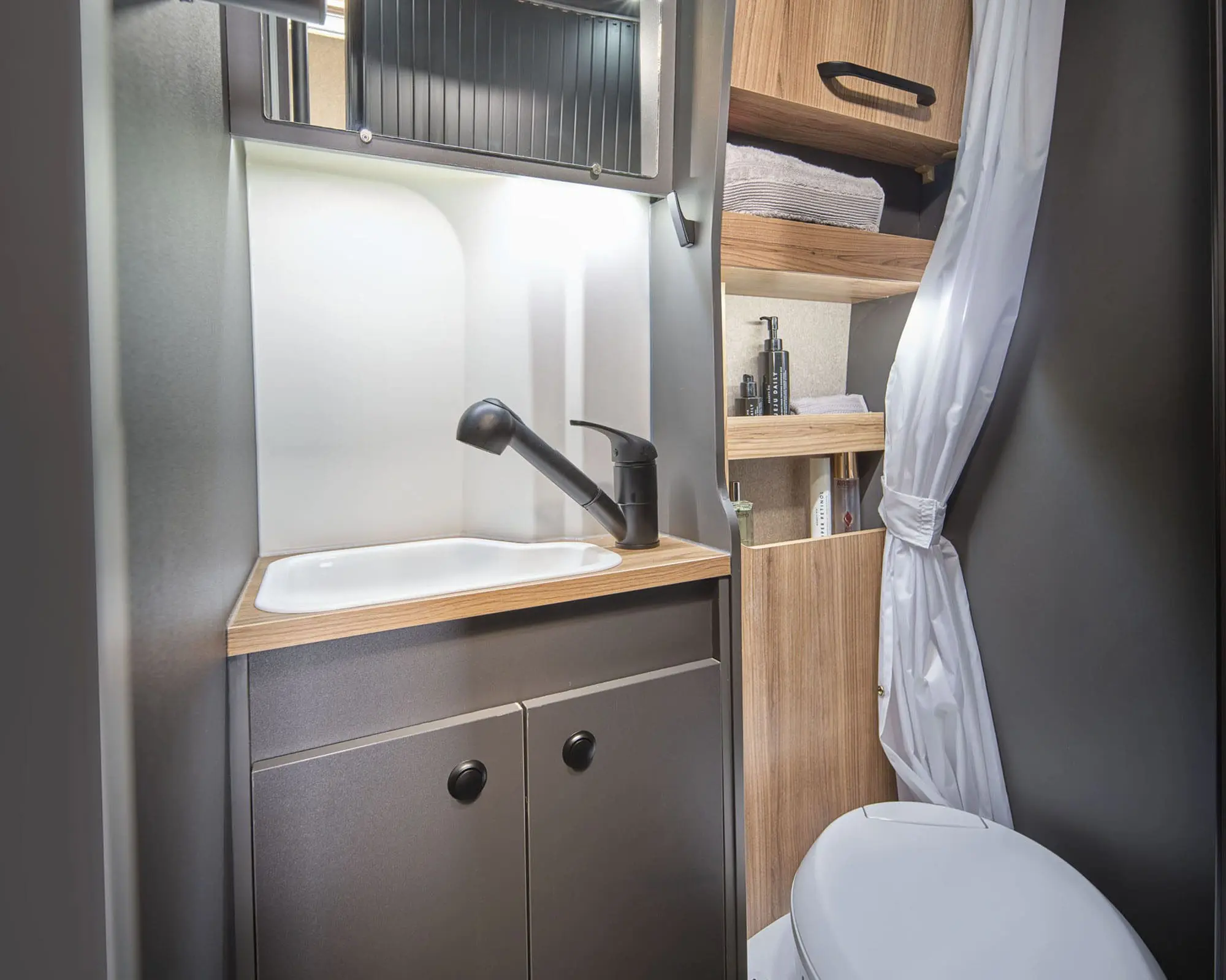 Elegant bathroom design in a Bailey caravan featuring a sink, toilet, and wooden shelves.