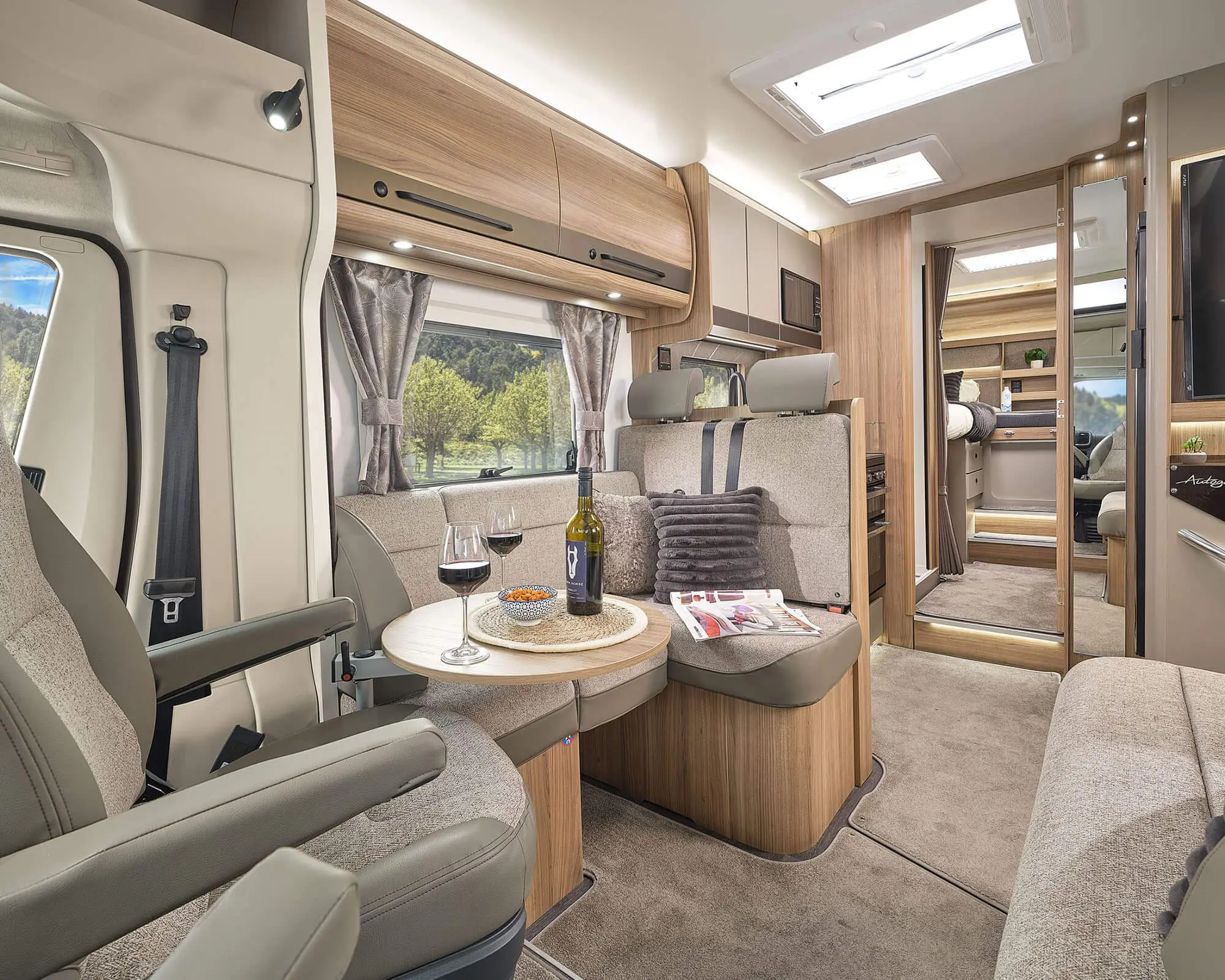 Stylish interior of a motorhome with lounge seating, a small table, and scenic views through the windows.