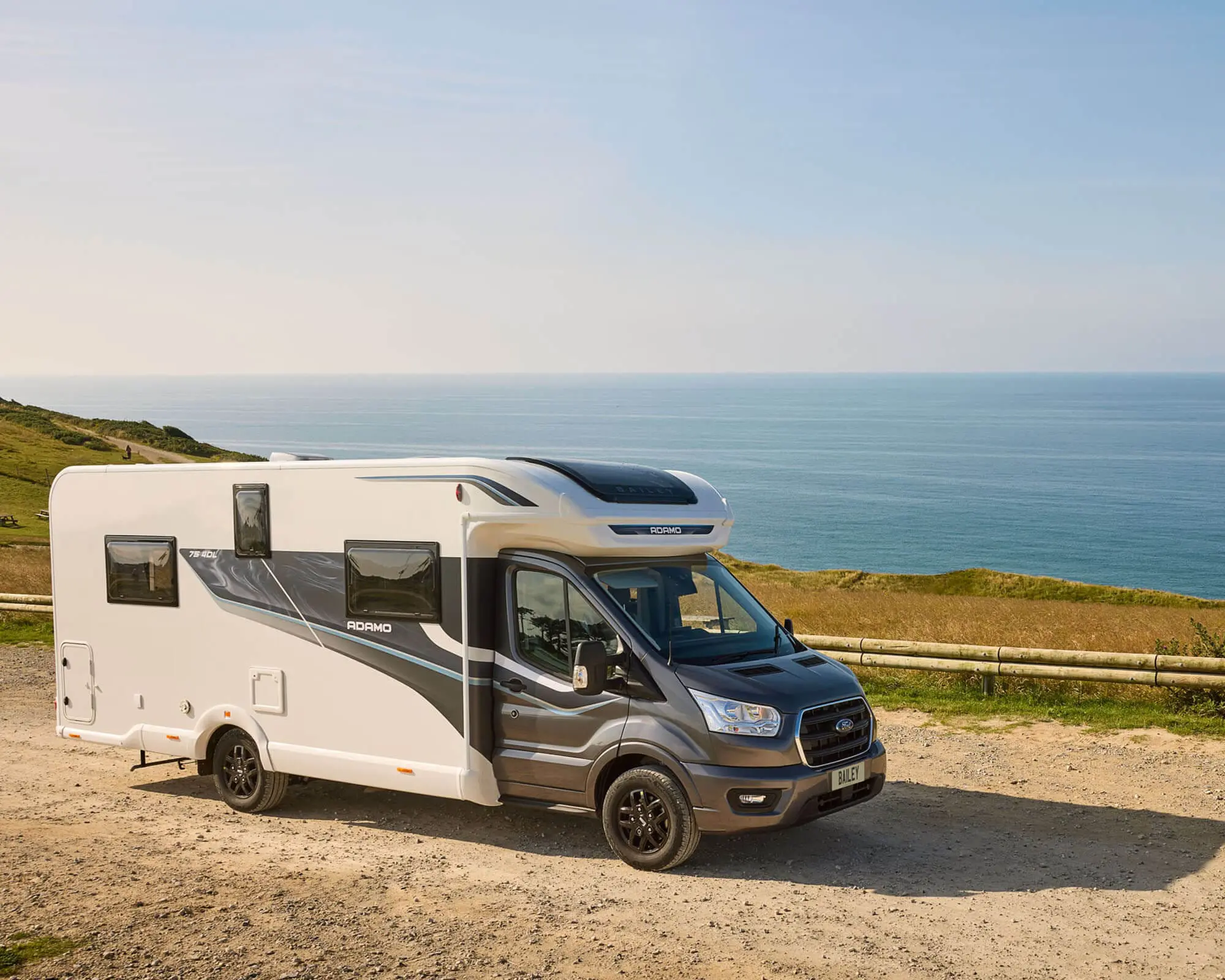 A Bailey motorhome parked on a coastal road with a scenic view of the ocean.