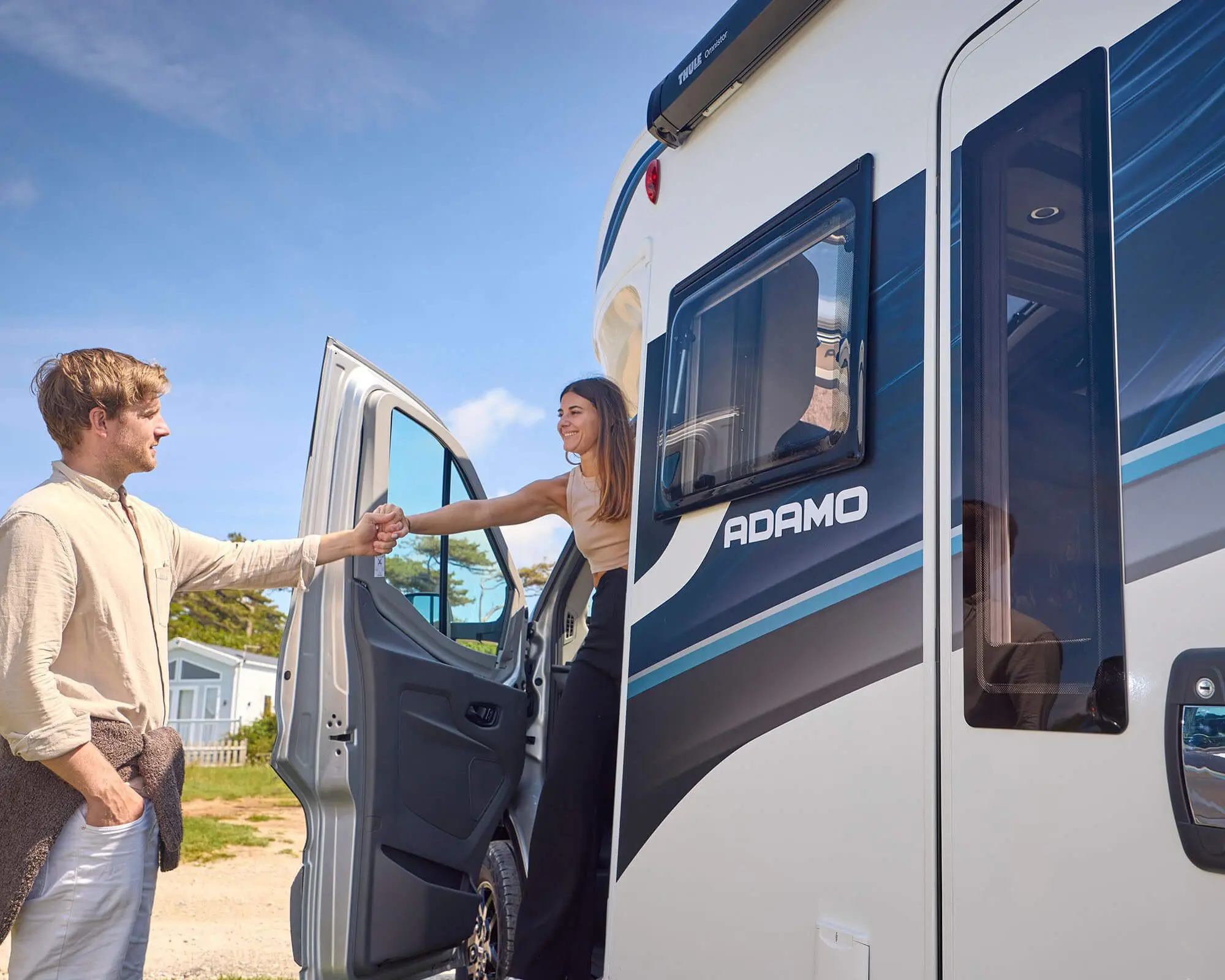 A couple standing by a Bailey Adamo motorhome, showcasing friendly interaction.