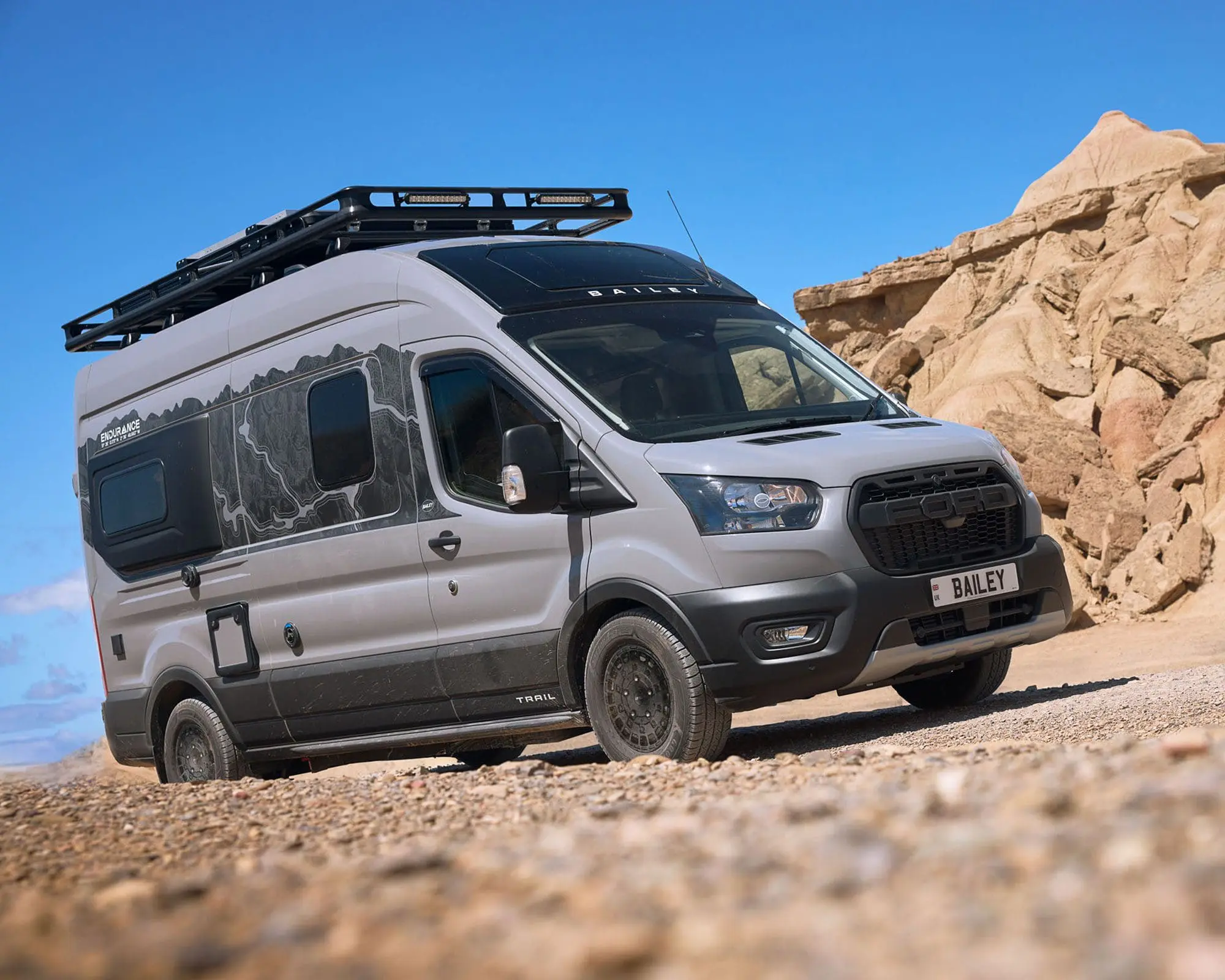 Grey Campervan parked on rocky ground, featuring a roof rack for added storage and outdoor adventure.