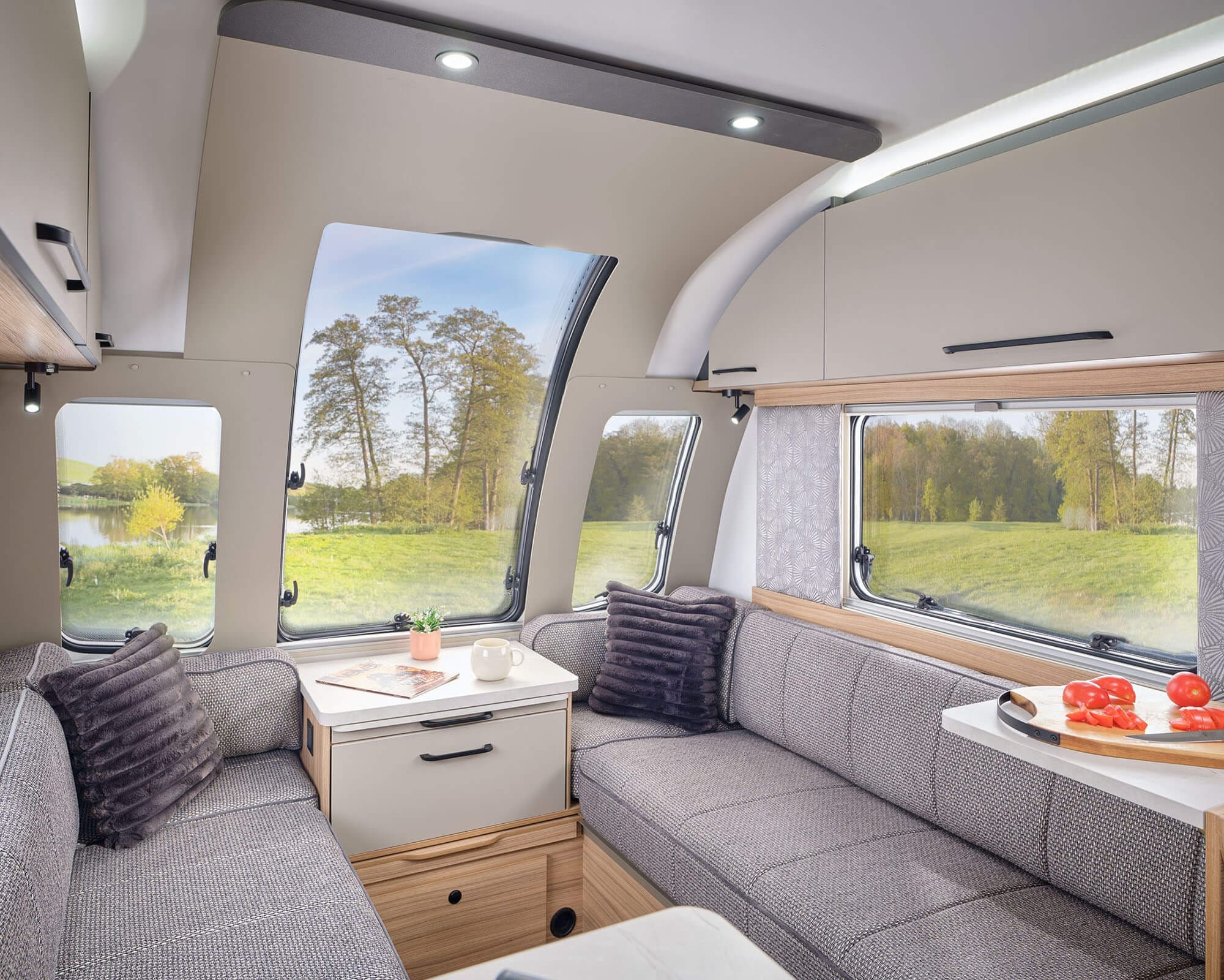 Cozy Interior of a Bailey Caravan with Scenic Views Inviting lounge area inside a Bailey caravan featuring modern furnishings and large windows overlooking a serene landscape.