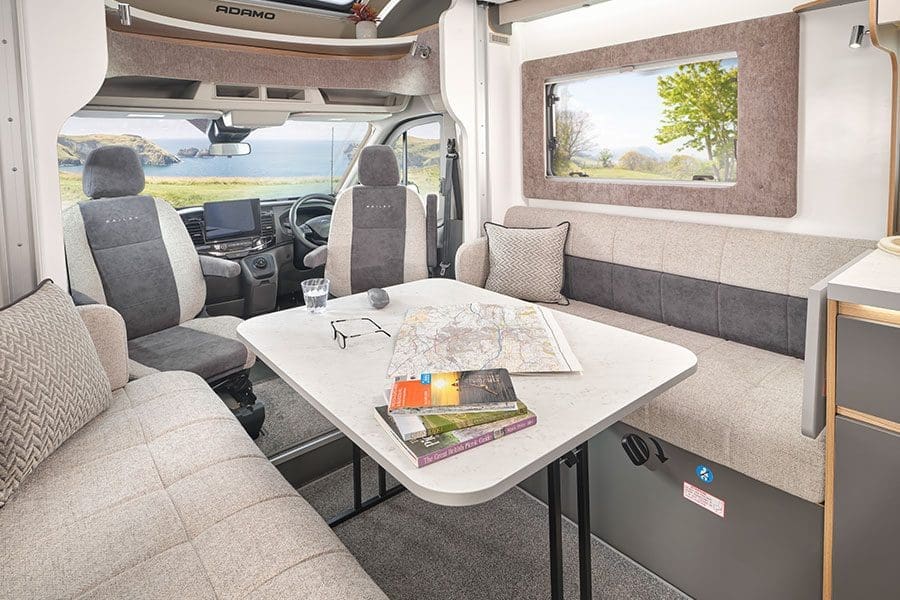 Interior view of a Bailey motorhome featuring a table, comfortable seating, and a scenic window view.