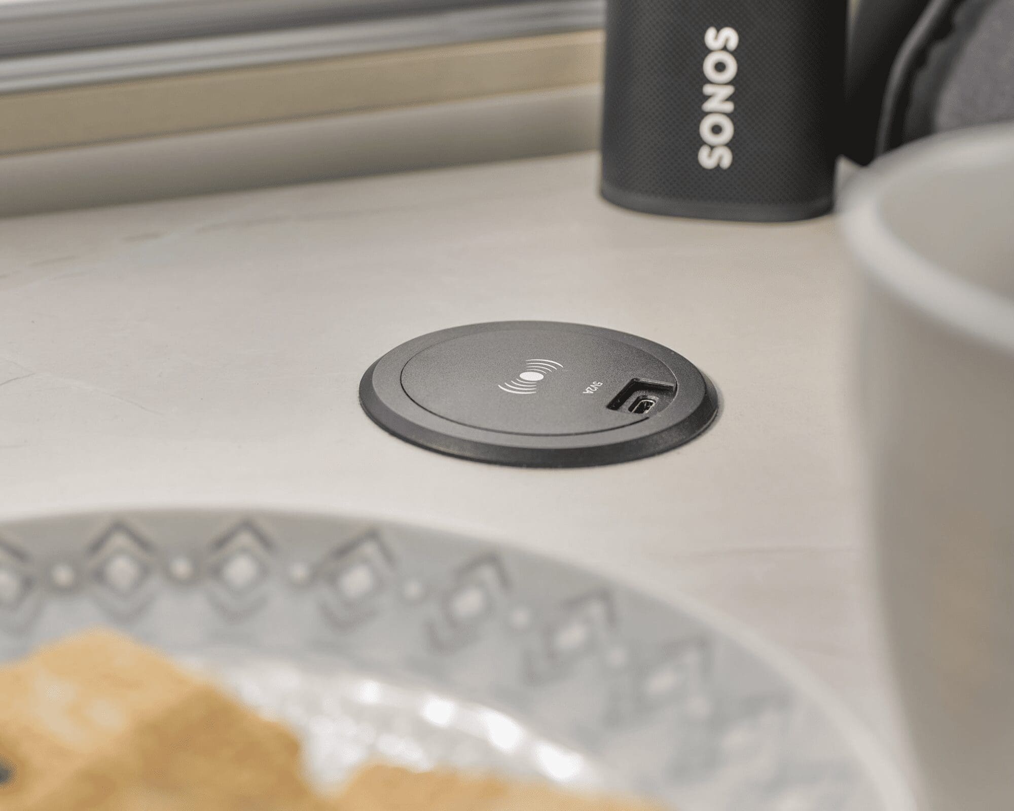 A close-up of a power socket on a countertop with a plate and a cup nearby, showcasing modern amenities in a caravan.