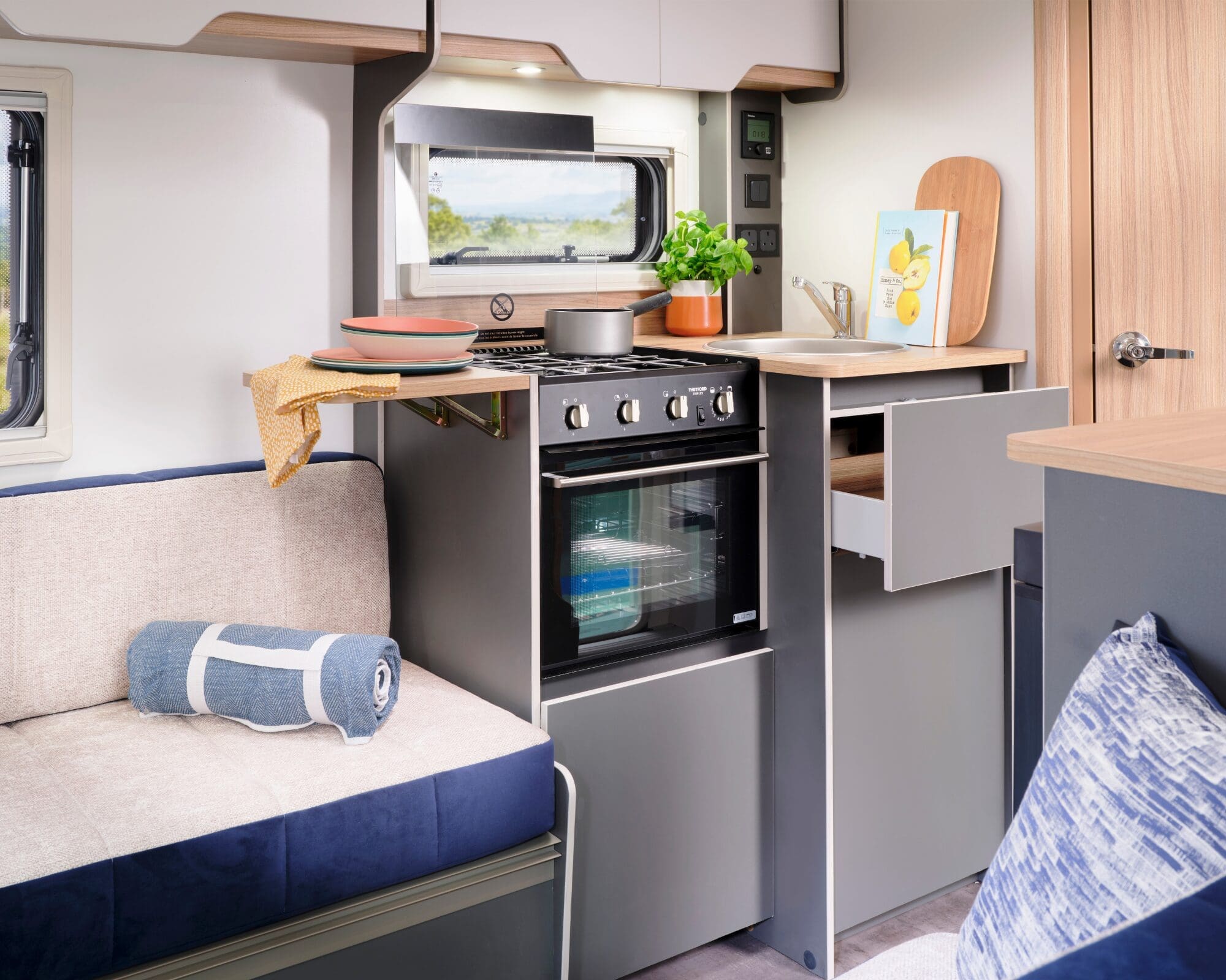 Cozy kitchen and seating area inside a Bailey caravan, featuring a stove, oven, and decorative elements.