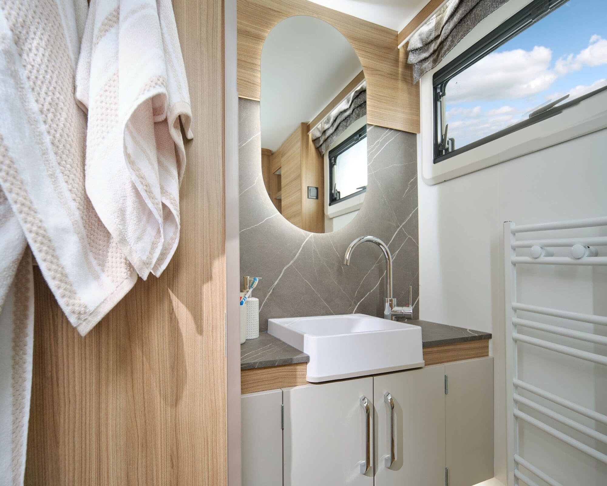 Modern bathroom design featuring a sink, mirror, and storage in a Bailey motorhome