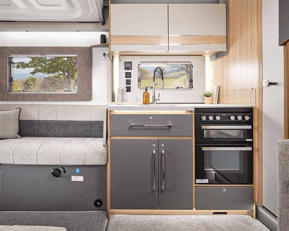 Interior view of a stylish caravan kitchen featuring a sink, stove, and storage cabinets